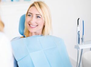Woman smiling in a dental chair, discussing the beauty of dental crowns.