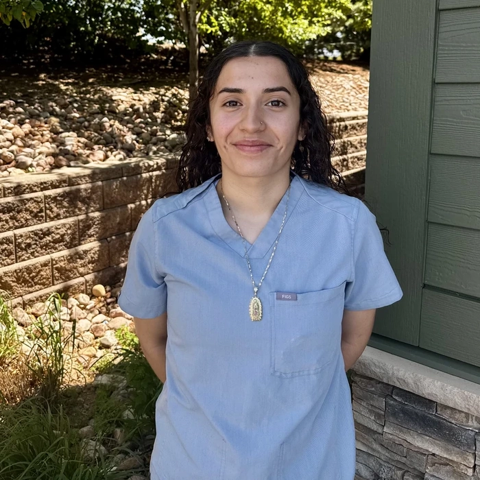 Green Dental Care team member in light blue scrubs.