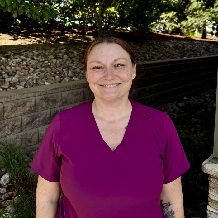 About Green Dental Care: smiling dental hygienist in purple scrubs